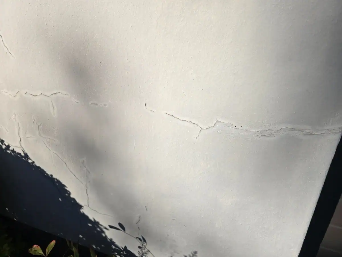 Cracks and damp-affected coating on an exterior wall before repairs at a Kanonberg Lifestyle Estate home in Bellville