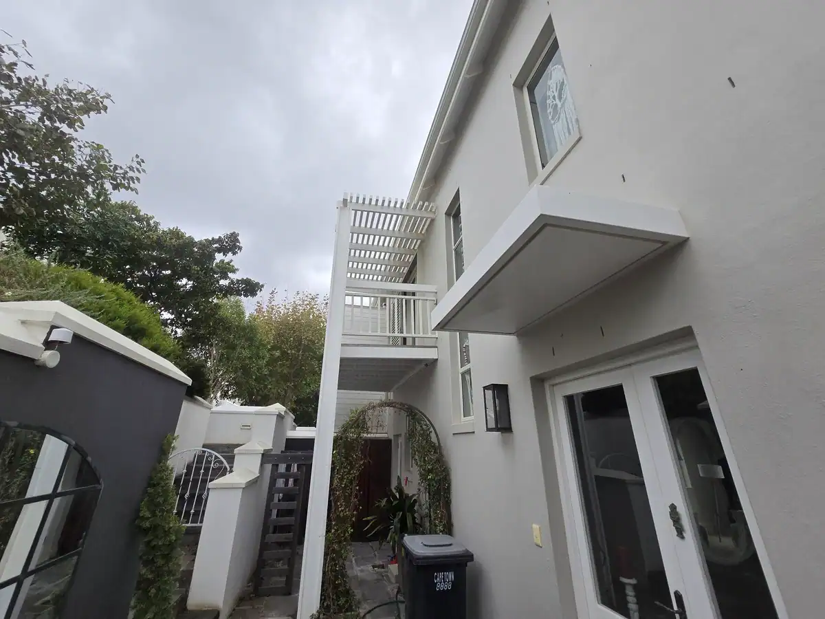 Completed exterior walls and wooden pergolas after repairs and painting at a Kenilworth Upper home