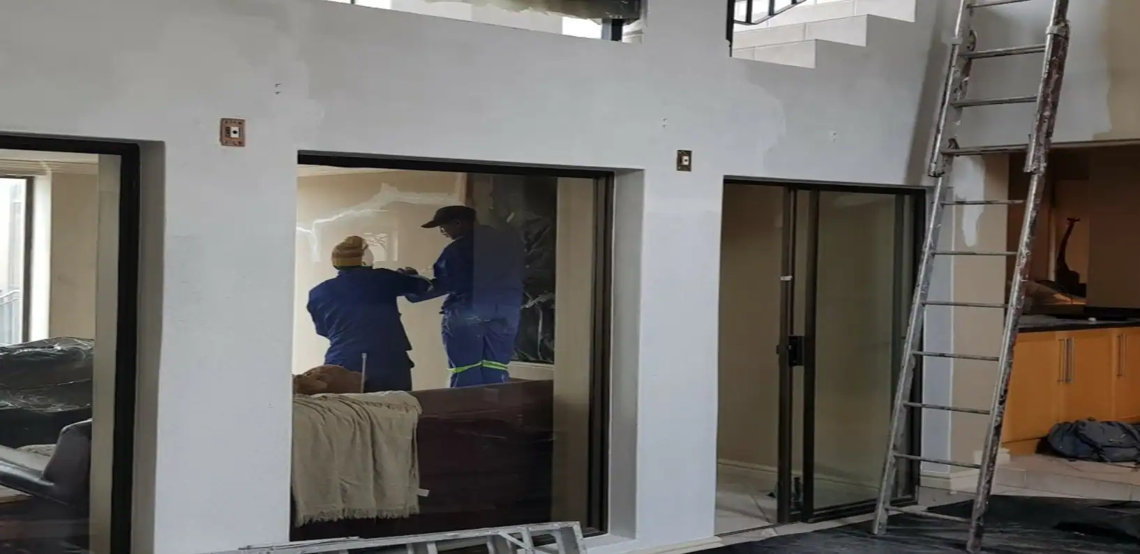 Painters preparing high interior walls and protecting furnishings during a full repaint at Hemel and Aarde Estate in Hermanus