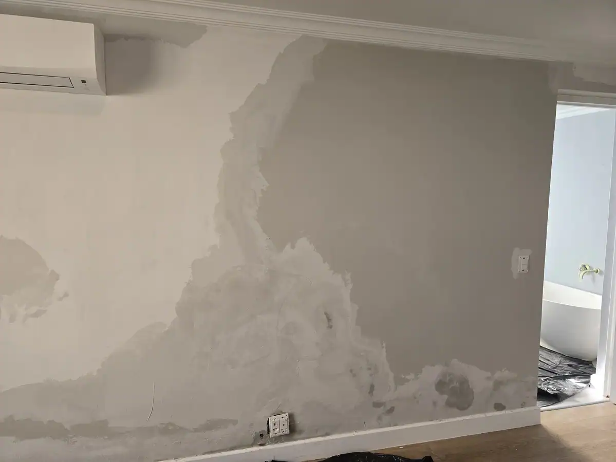 Damp-damaged bedroom wall after loose paint was removed and the surface prepared at L’Ermitage Estate in Franschhoek