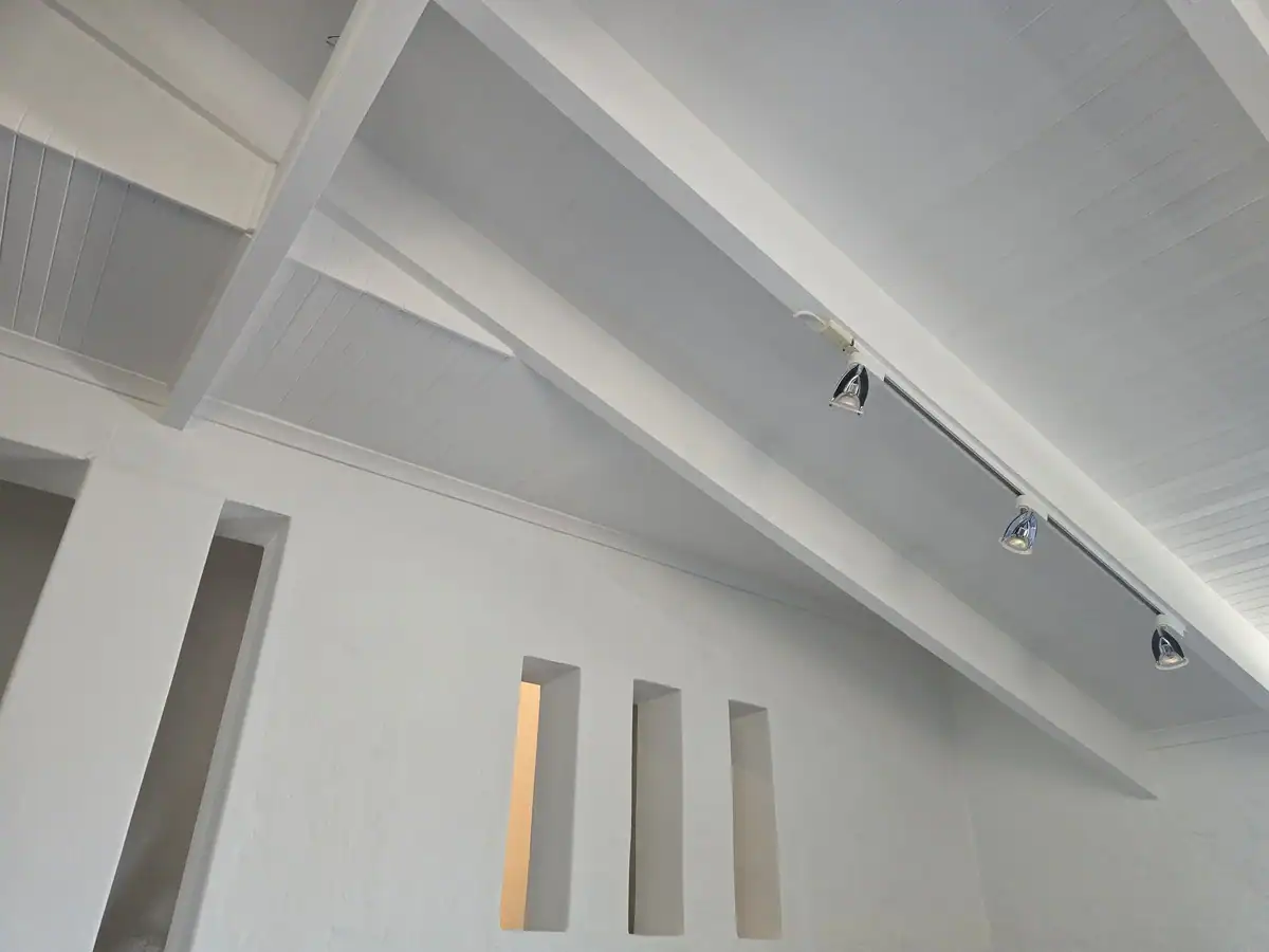 Double-volume wooden ceiling and exposed trusses after repairs and interior painting at a Courtrai home in Paarl North